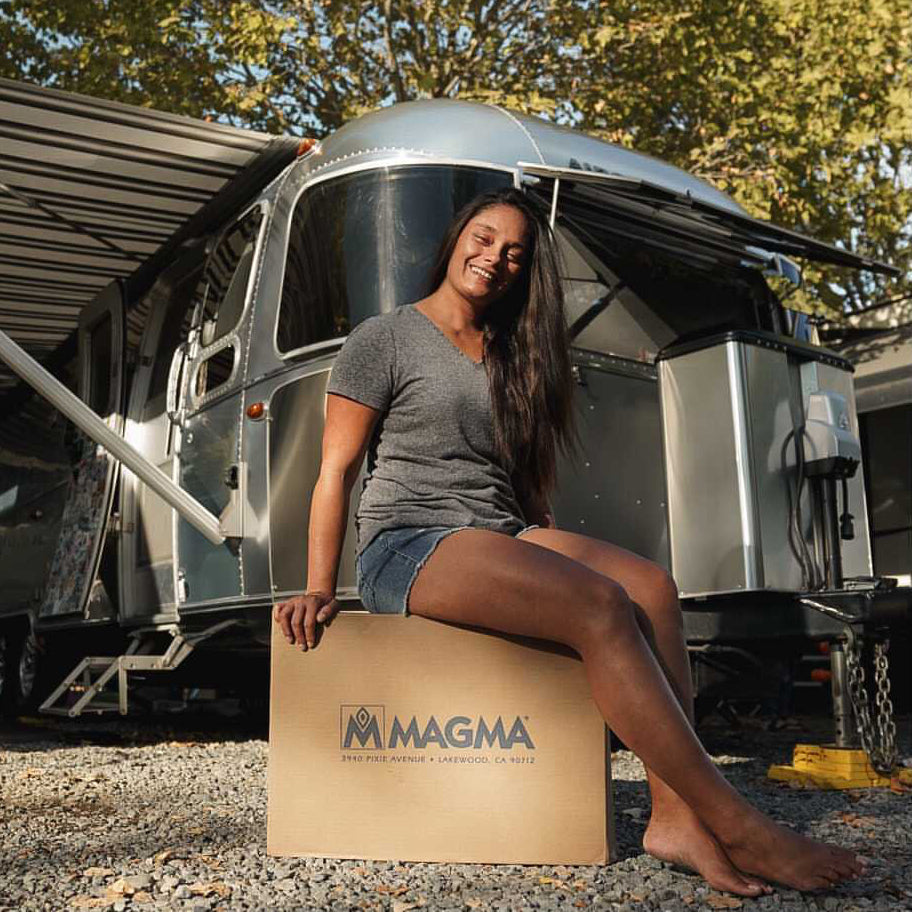 Woman sitting on a Magma grill package in front of her airstream trailer